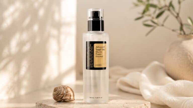 COSRX Snail Mucin Essence bottle with snail shell on beige background