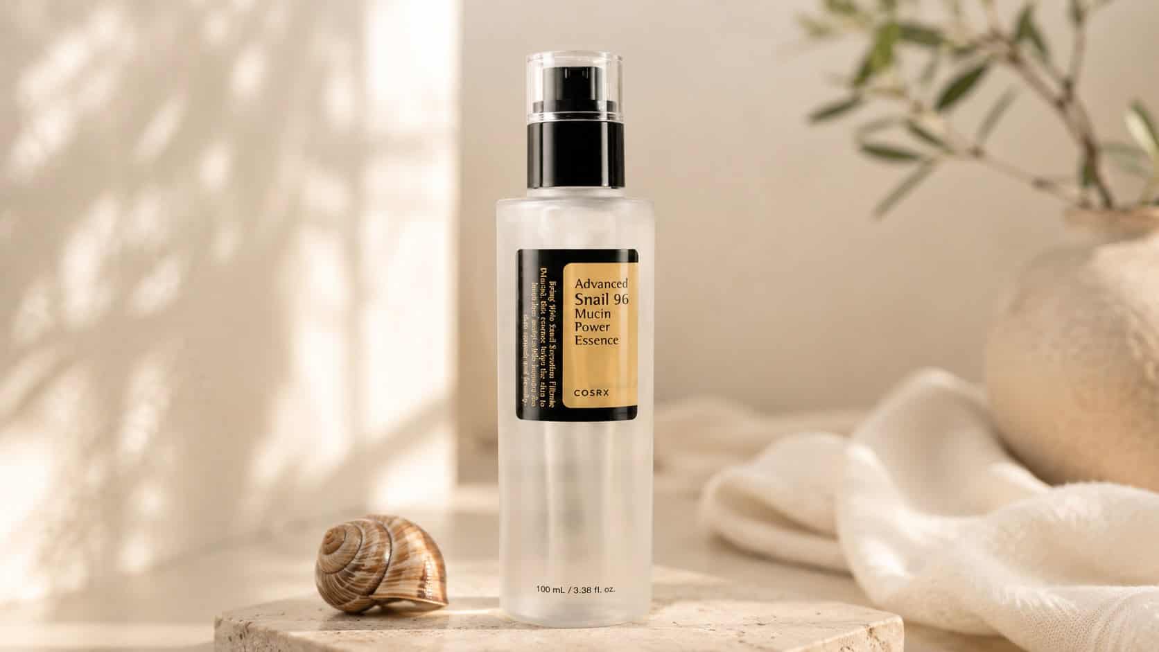 COSRX Snail Mucin Essence bottle with snail shell on beige background