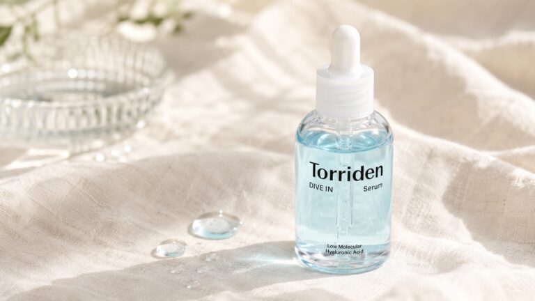 Torriden DIVE-IN Hyaluronic Acid Serum bottle on cream linen with water droplets