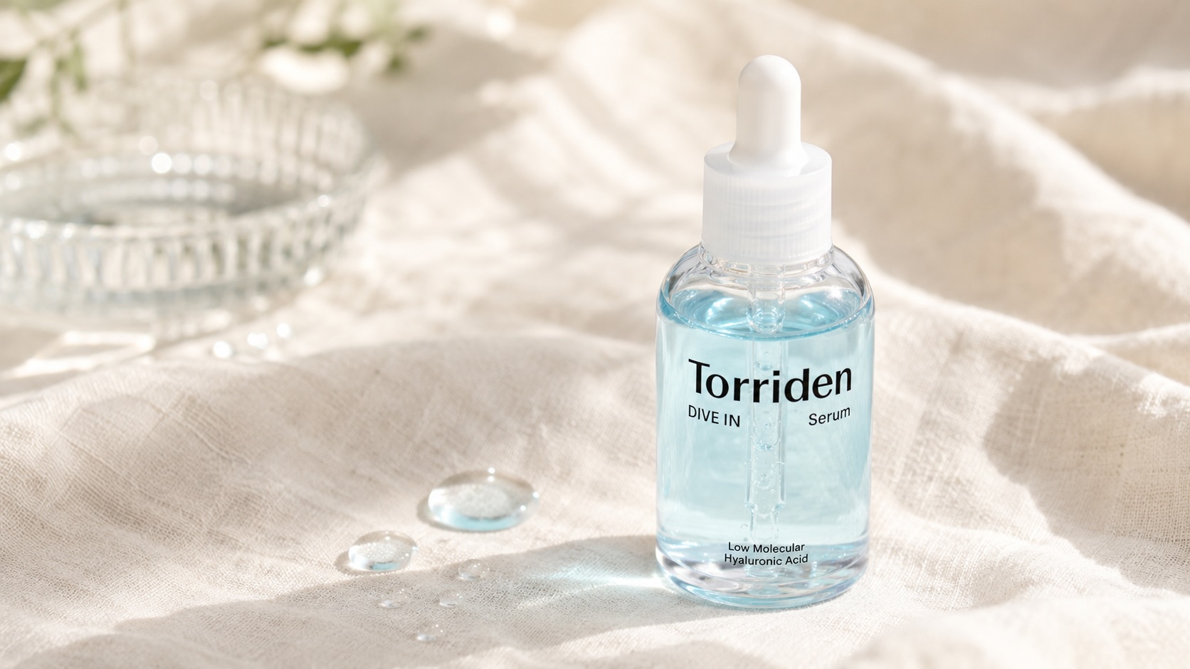 Torriden DIVE-IN Hyaluronic Acid Serum bottle on cream linen with water droplets